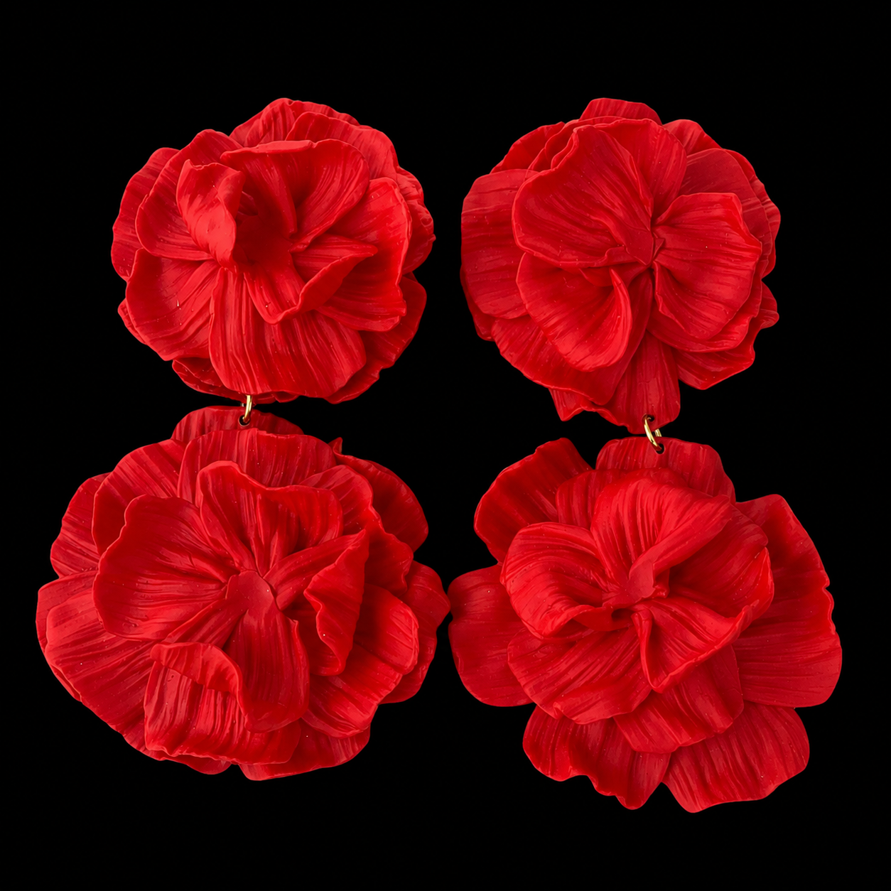 Four red flower-shaped earrings arranged in a 2x2 grid on a solid black background.